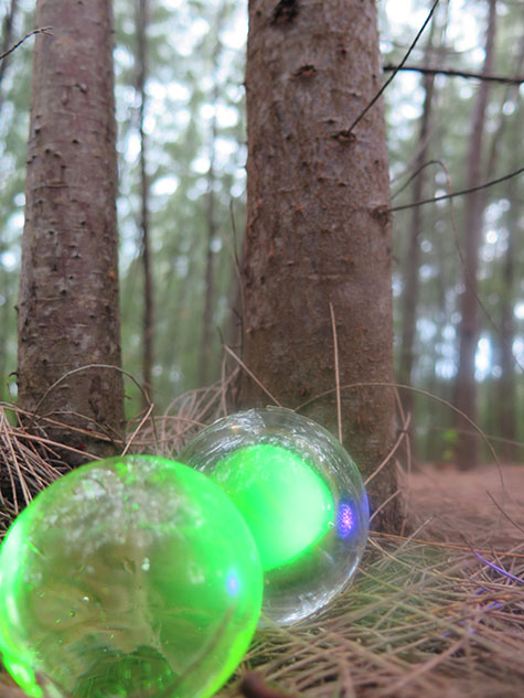 Handblown glass orbs in the forest, pond, and on the shore